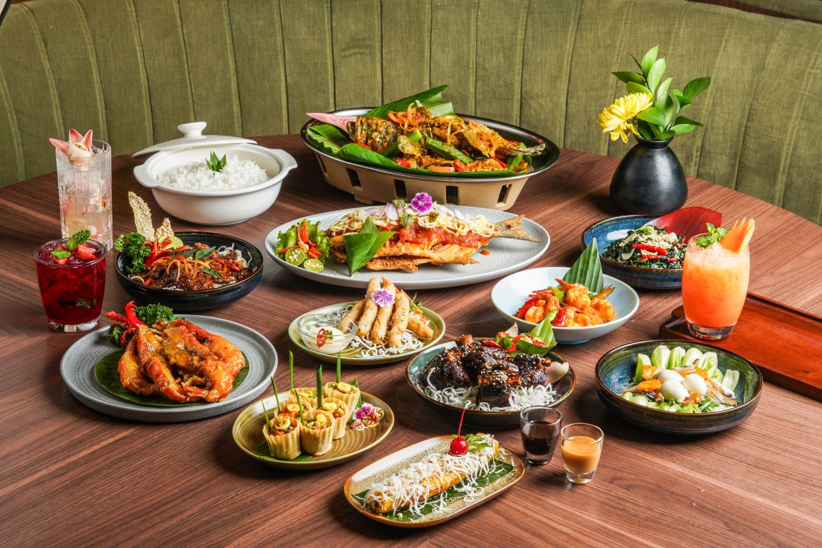 An overhead spread of many Padang dishes on small plates, showcasing rendang, gulai, sambal, and other signature sides