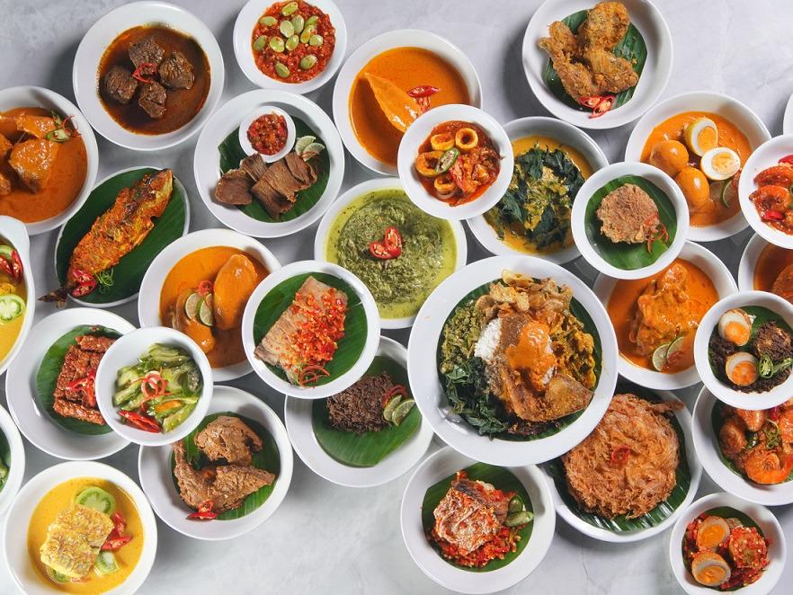 A full table spread of Indonesian dishes served family-style at Rumah Rasa, including grilled crab, whole fried fish, satay, and rice